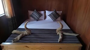 A bed with striped bedding, two pillows with black stripes, and two horns placed on the bed. - Dolphin Bay Cabana Resort (Trincomalee)