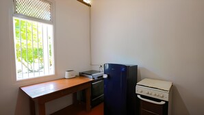 A small kitchen with a wooden table, a toaster, a stove, and a refrigerator. - Dolphin Bay Cabana Resort (Trincomalee)