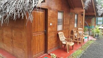 Guests can enjoy a peaceful seating area outside with two chairs and a table, surrounded by a lush garden.