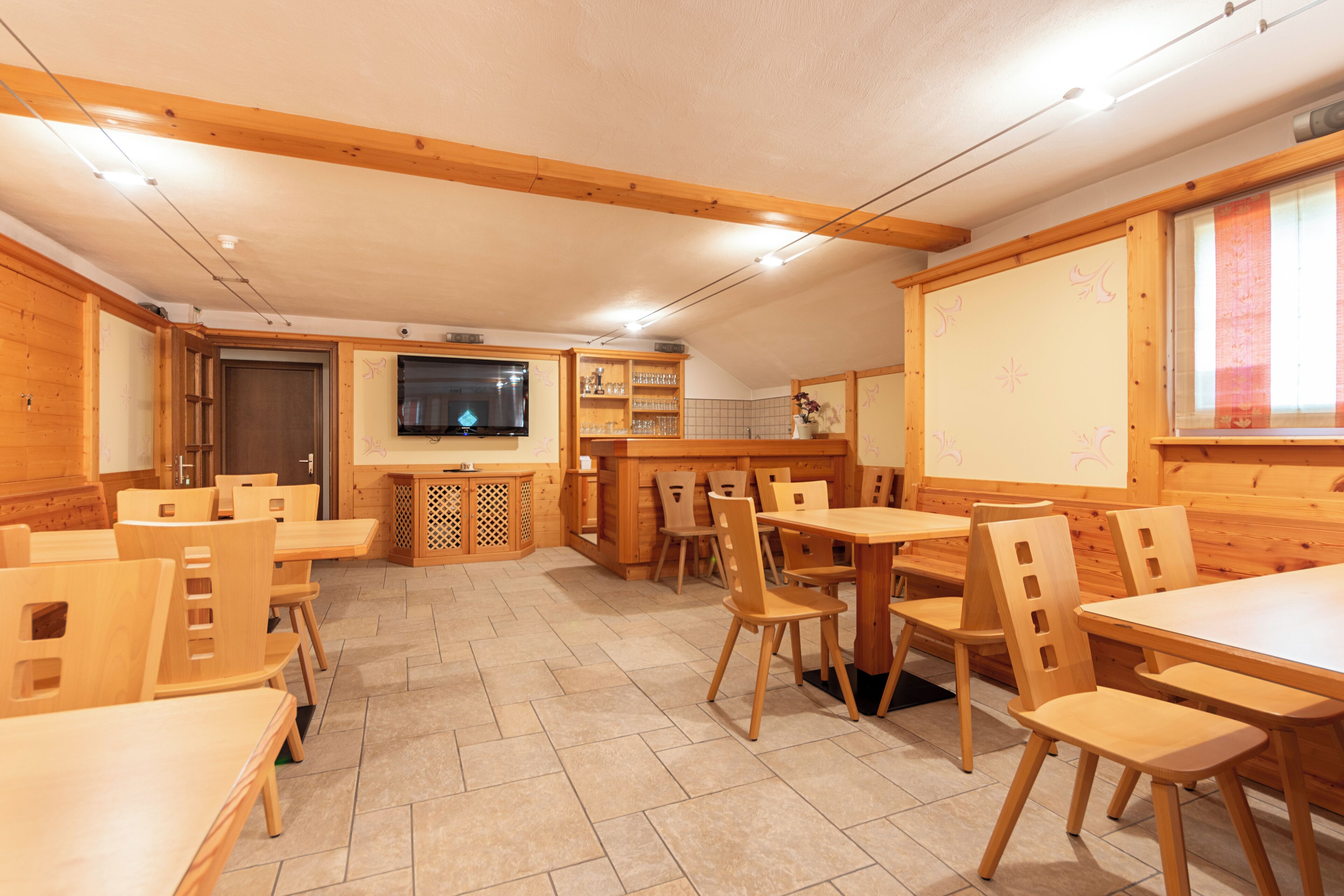 A restaurant with wooden furniture, a TV, and a whiteboard.