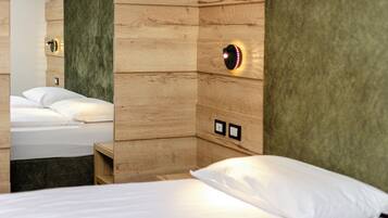 Habitación de hotel con paneles de madera, una cama con ropa blanca y una lámpara fijada a la pared.