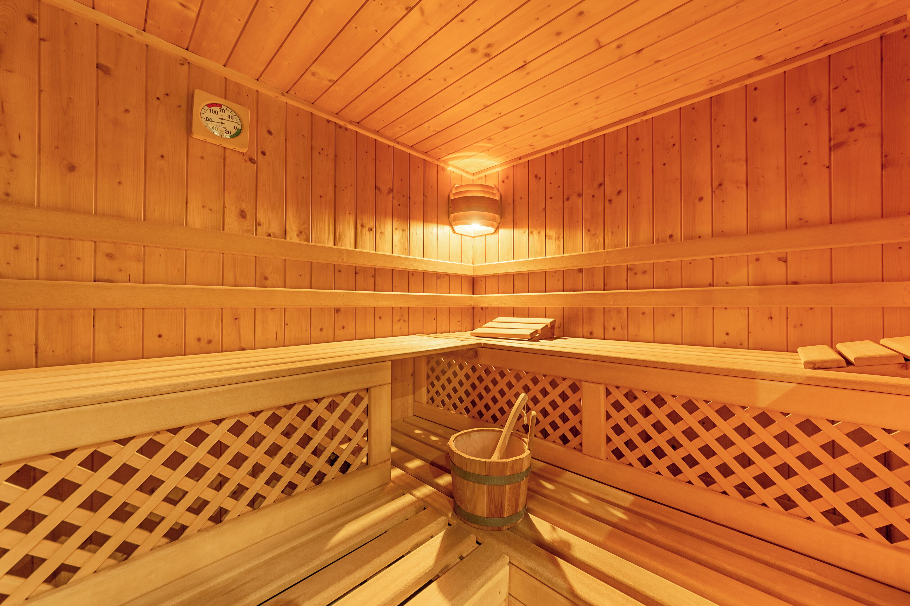A wooden sauna with benches and a bucket.