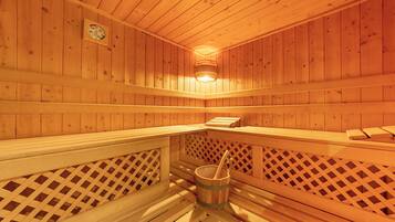 A wooden sauna with benches and a bucket.