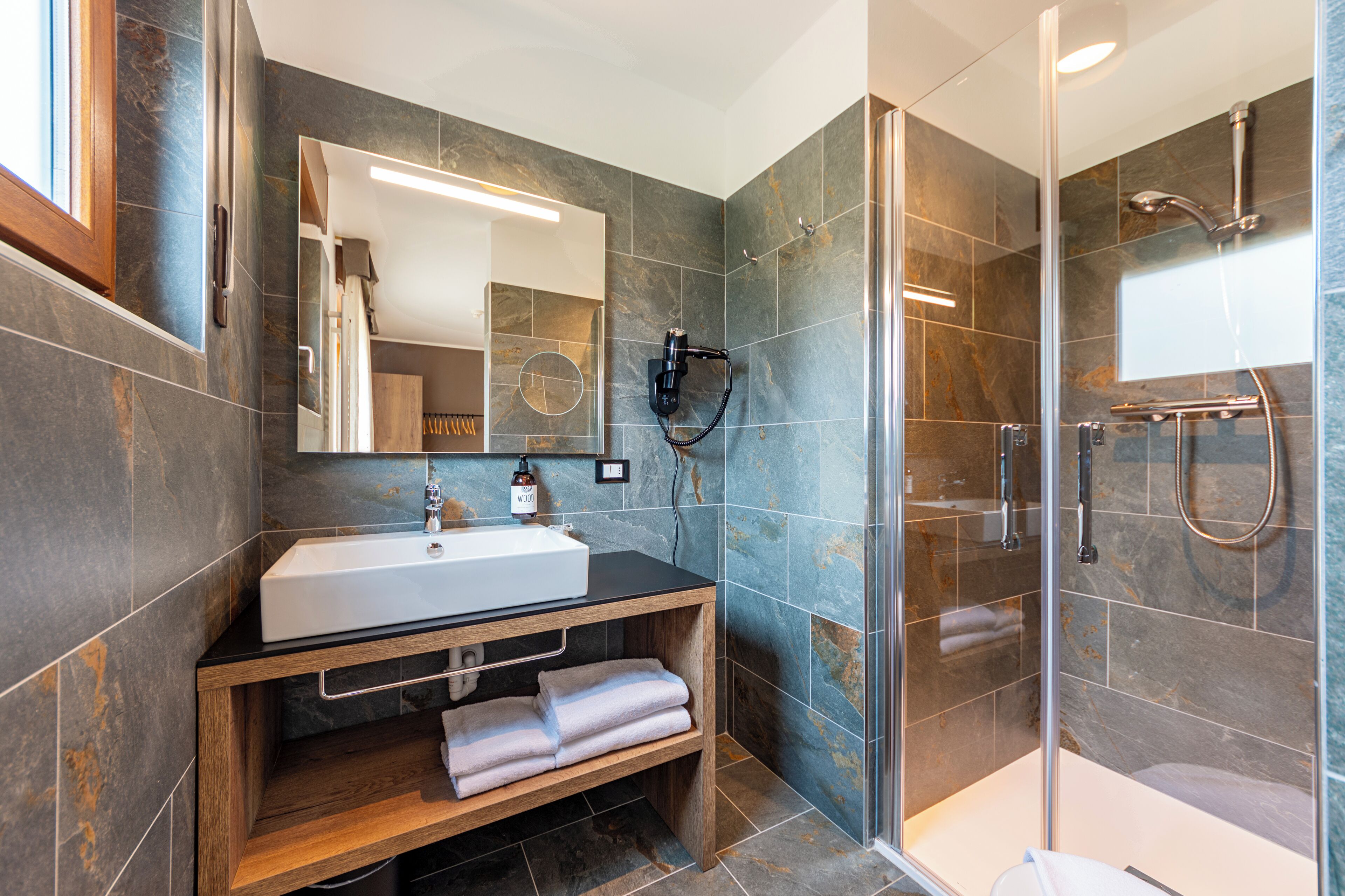 A modern bathroom with a large sink, mirror, and shower area.