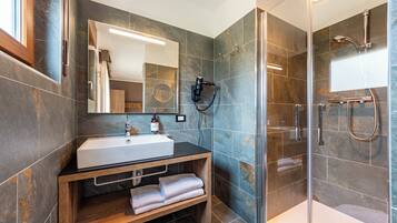 Un baño moderno con un lavamanos grande, un espejo y una zona de ducha.