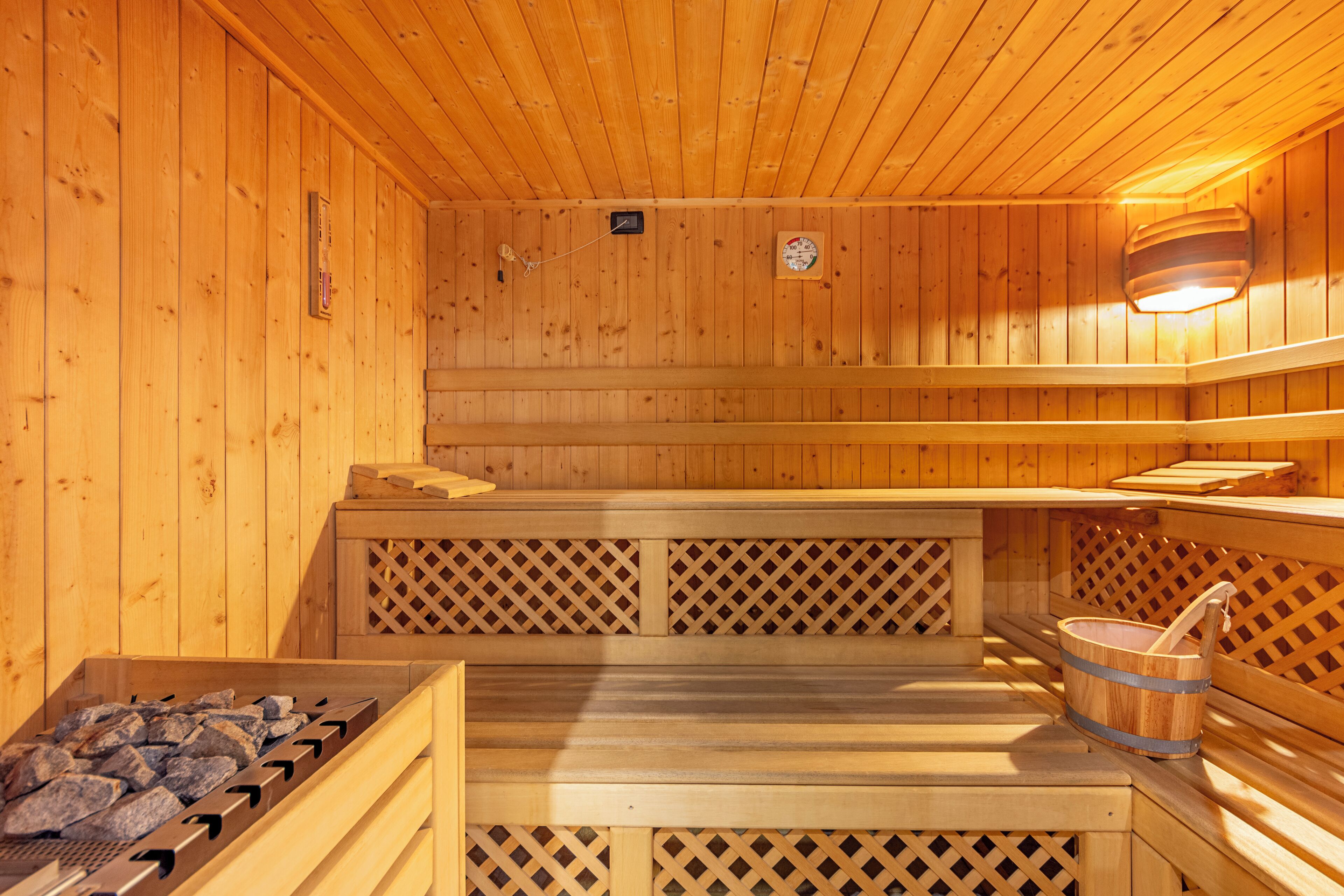 A wooden sauna with benches and a stone heating element.