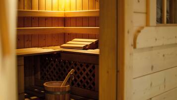 A sauna with wooden benches and a wooden bucket.