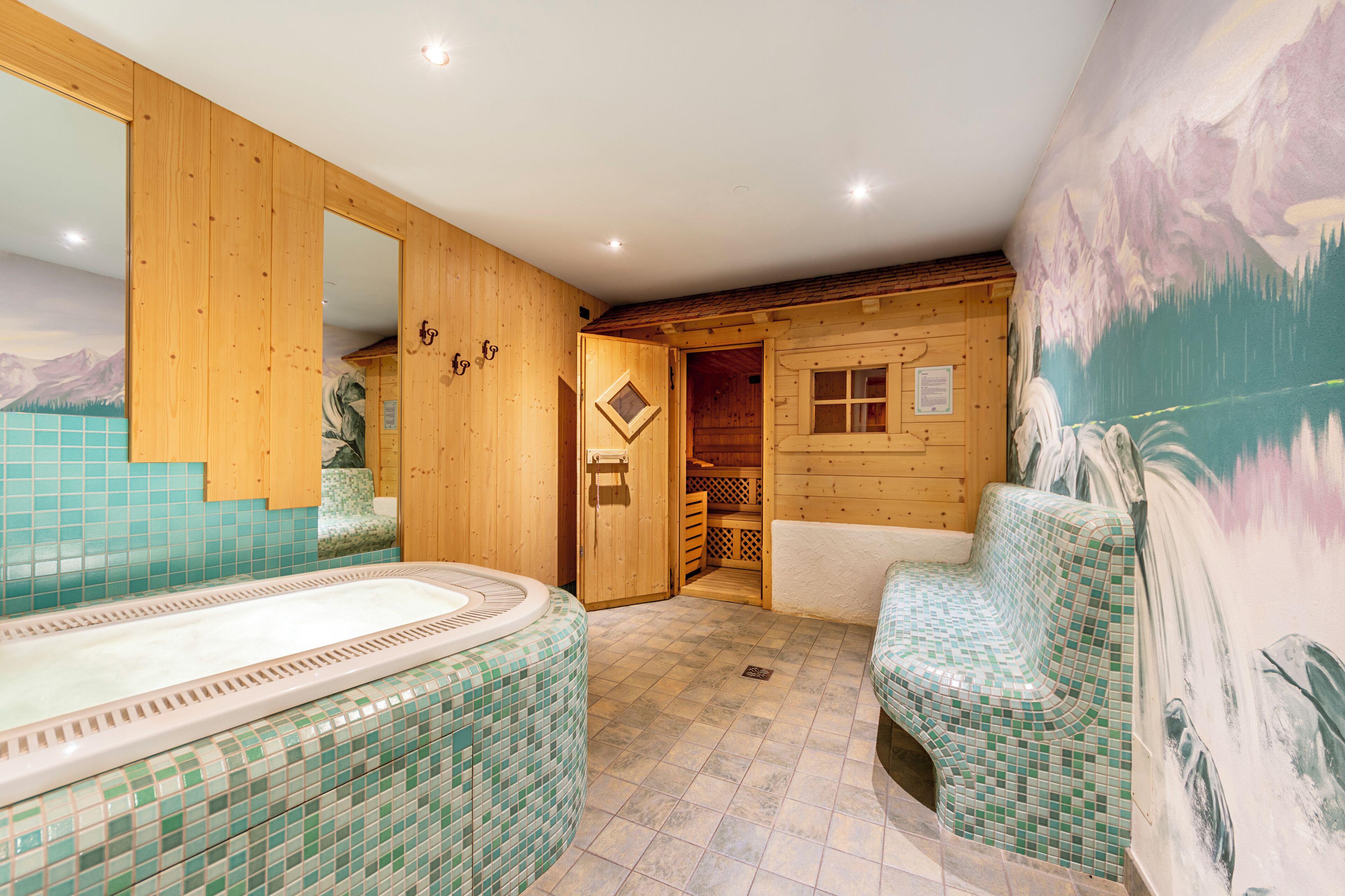 Un spa con paredes de madera, suelo de mosaico, un espejo grande y un mural de un paisaje montañoso.