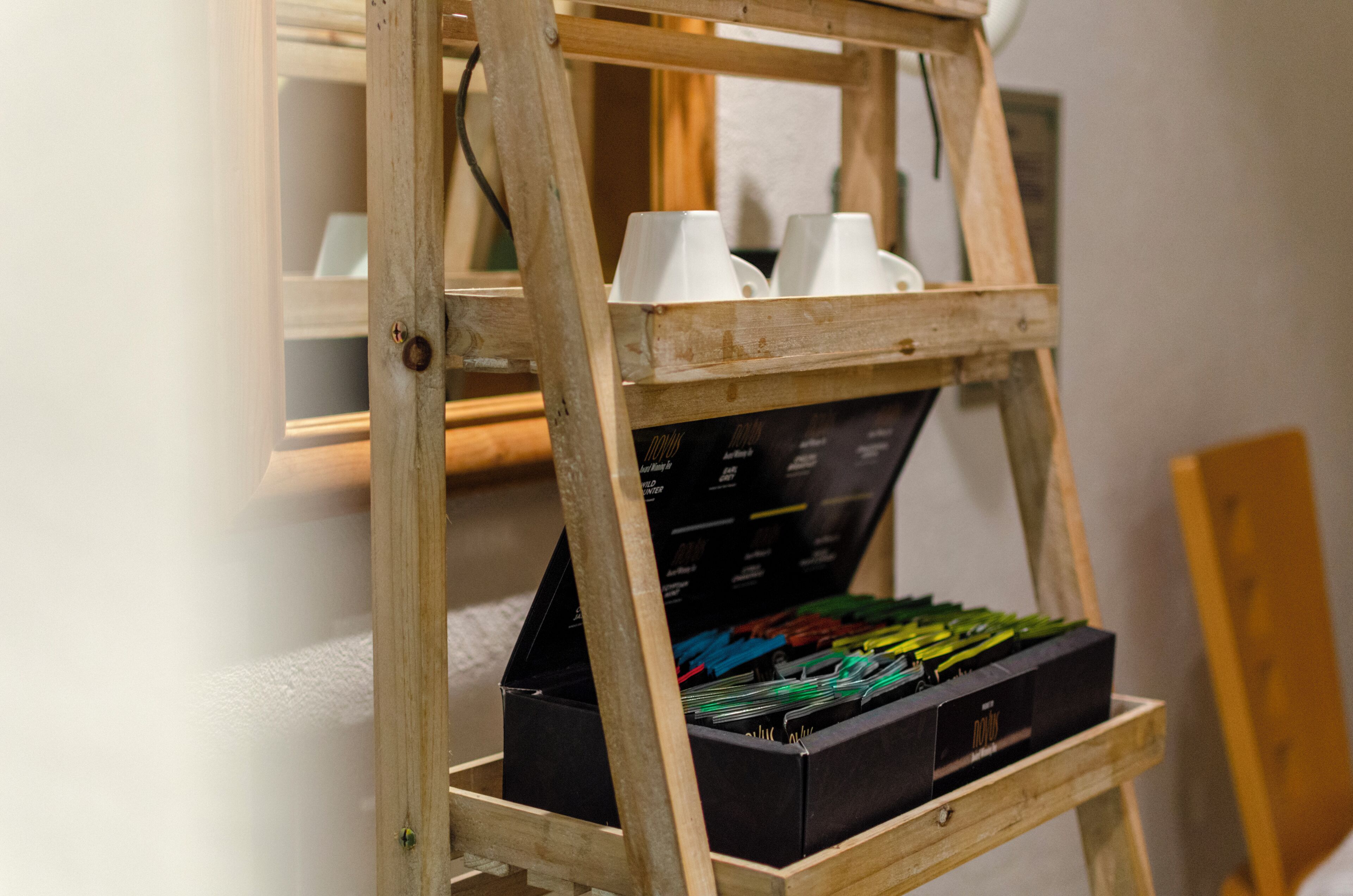 A wooden ladder with cups and a box of colorful items.
