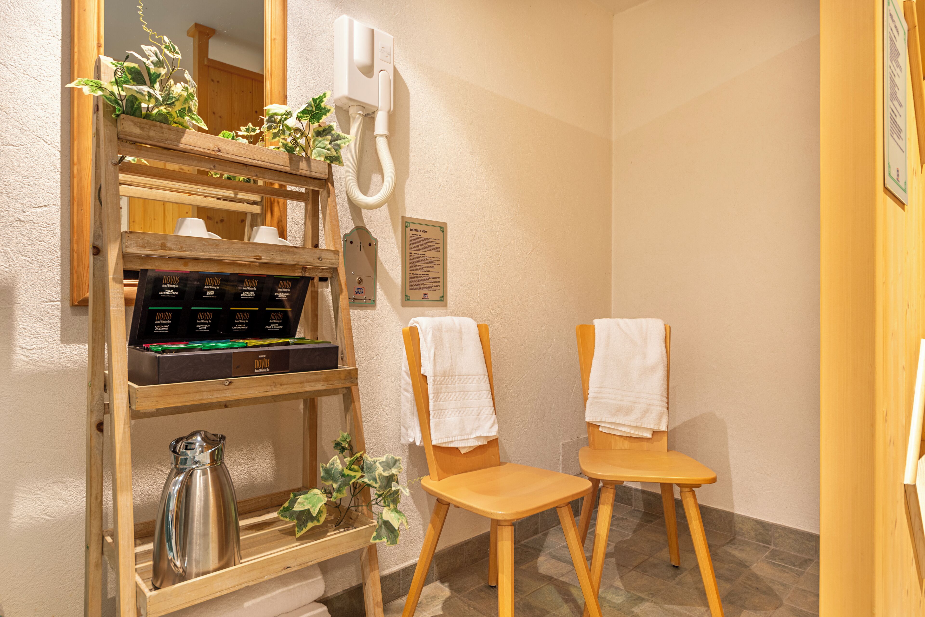 Un baño con sillas de madera, un estante con artículos de aseo y un espejo.