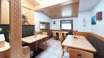 Ein Restaurant mit Holztischen und -sitzen, einem Fliesenboden und Blick ins Freie durch ein Fenster.