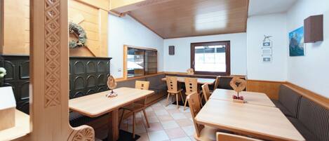A restaurant with wooden tables and booths, a tiled floor, and a view of the outdoors through a window.