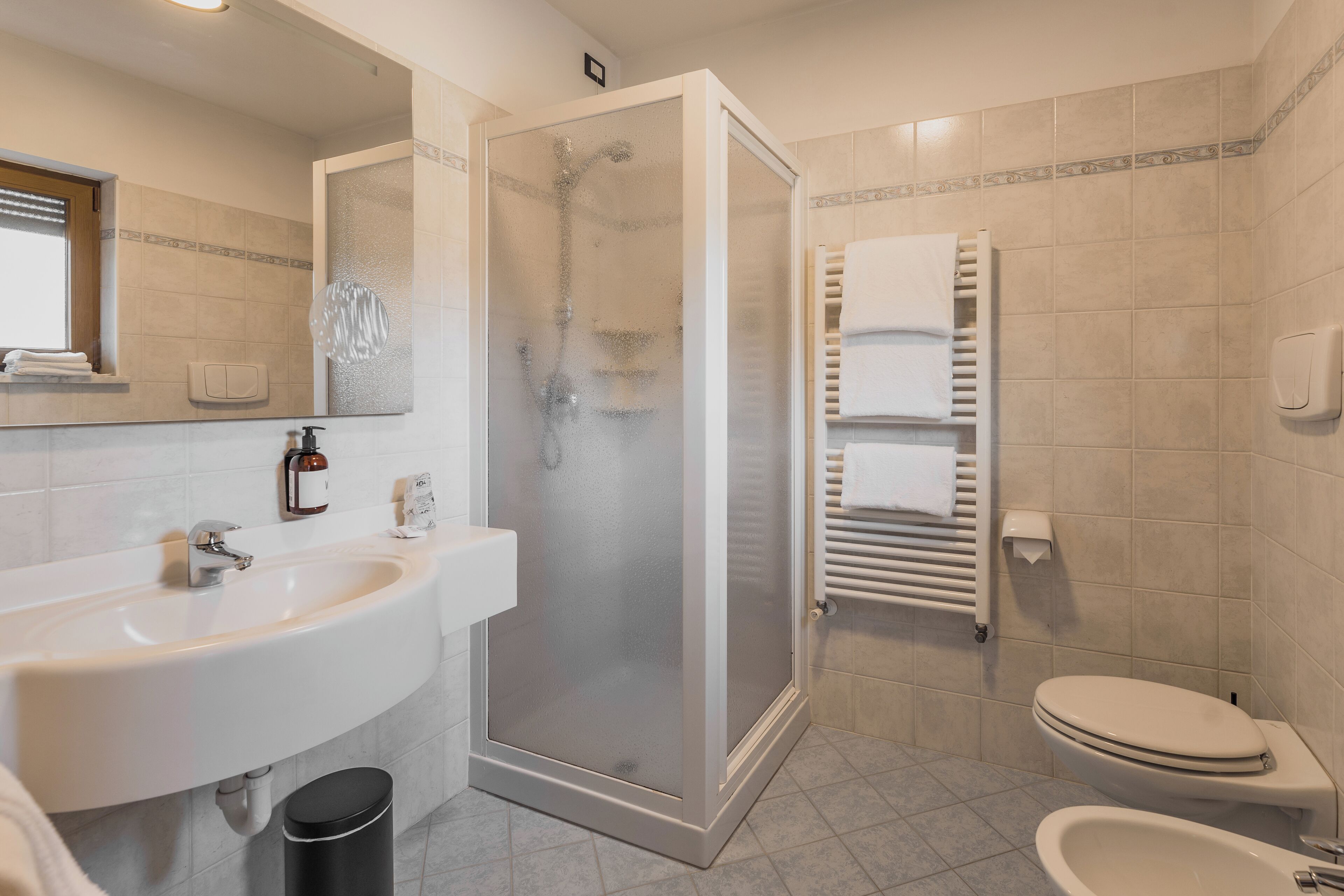 A modern bathroom with a glass-enclosed shower, a white sink, and a toilet.