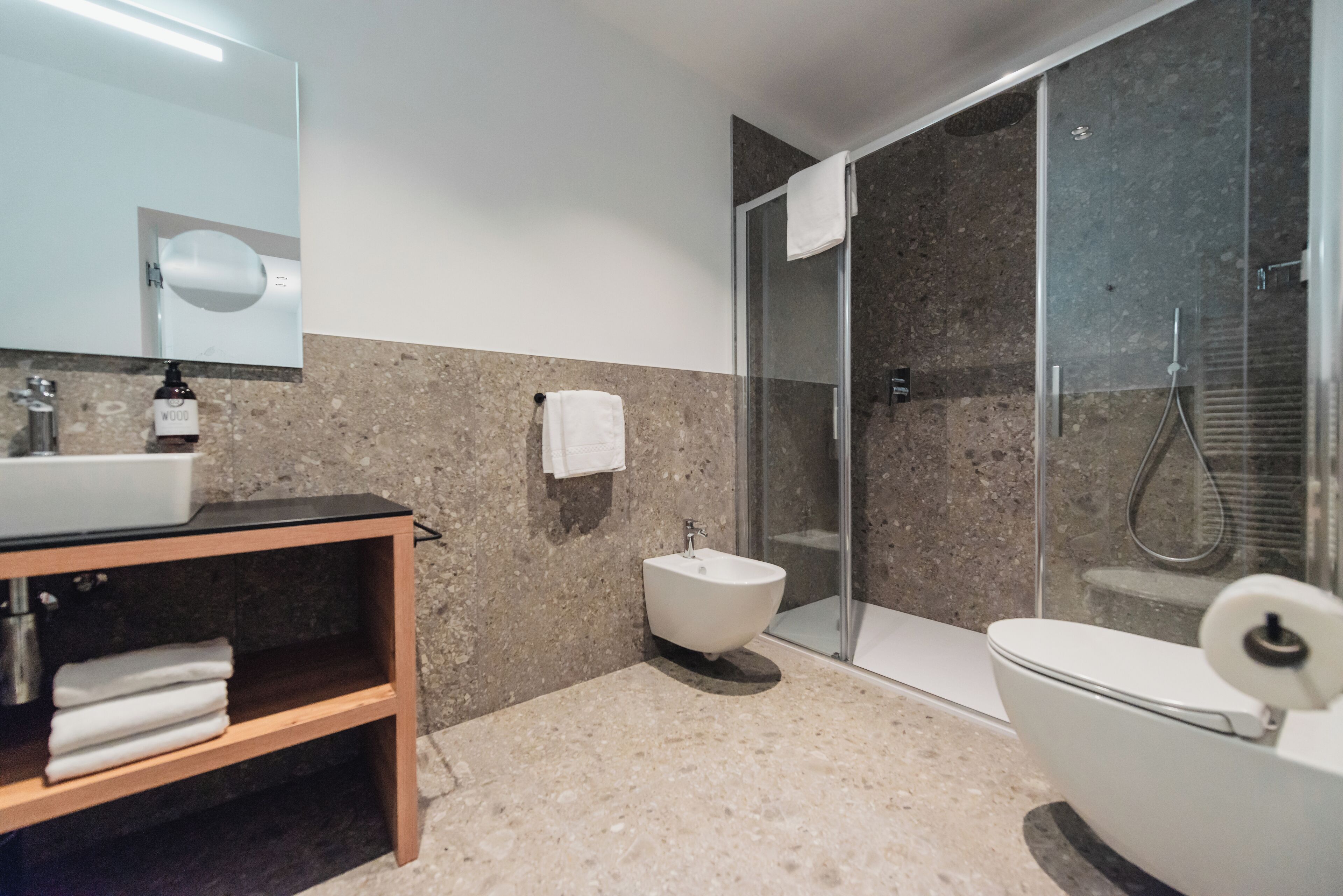 A modern bathroom with a sink, bidet, toilet, and a glass shower enclosure.