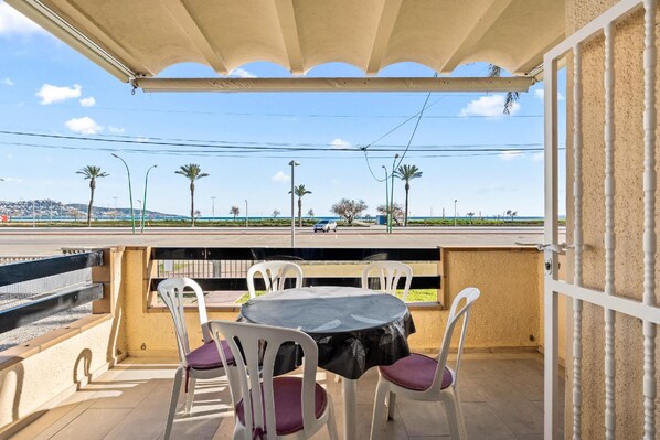 Enjoy a seaside view from this balcony with a table and chairs.