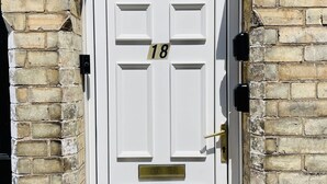 A white door with the number 18, set in a brick wall with a window above. - 18 Horner Street York (York)