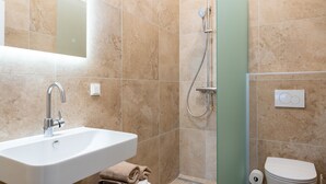 A bathroom with a sink, shower, toilet, and a towel rack.