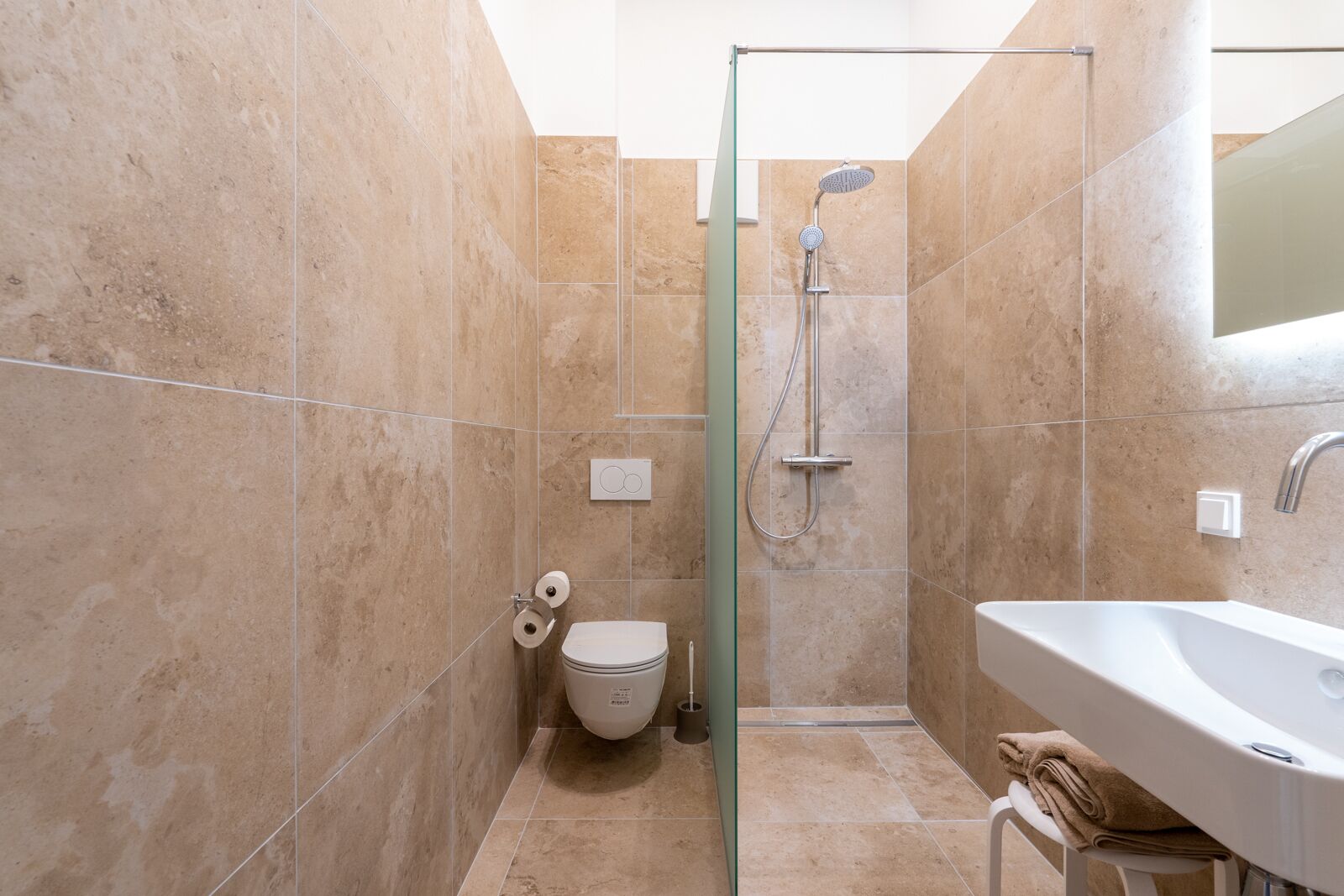 A modern bathroom with a glass shower enclosure, a white sink, and a toilet.