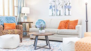 Una sala de estar con un sofá, sillones, una mesita de centro y un tapete estampado.
