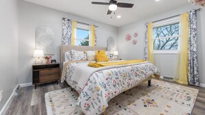Un dormitorio con cama, mesita de noche, lámpara y decoración mural.