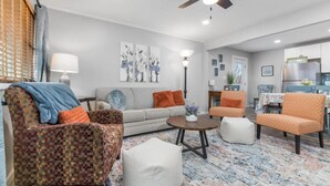 Una sala de estar moderna con un sofá, sillones, una mesa de centro y un ventilador de techo.