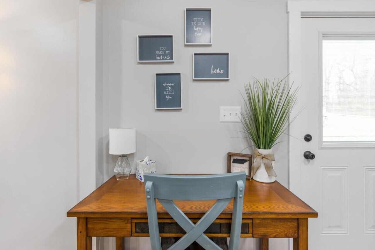 A dining area with a wooden table, a blue chair, and framed inspirational quotes on the wall.