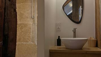 Une salle de bain avec un grand miroir, un lavabo et une douche.
