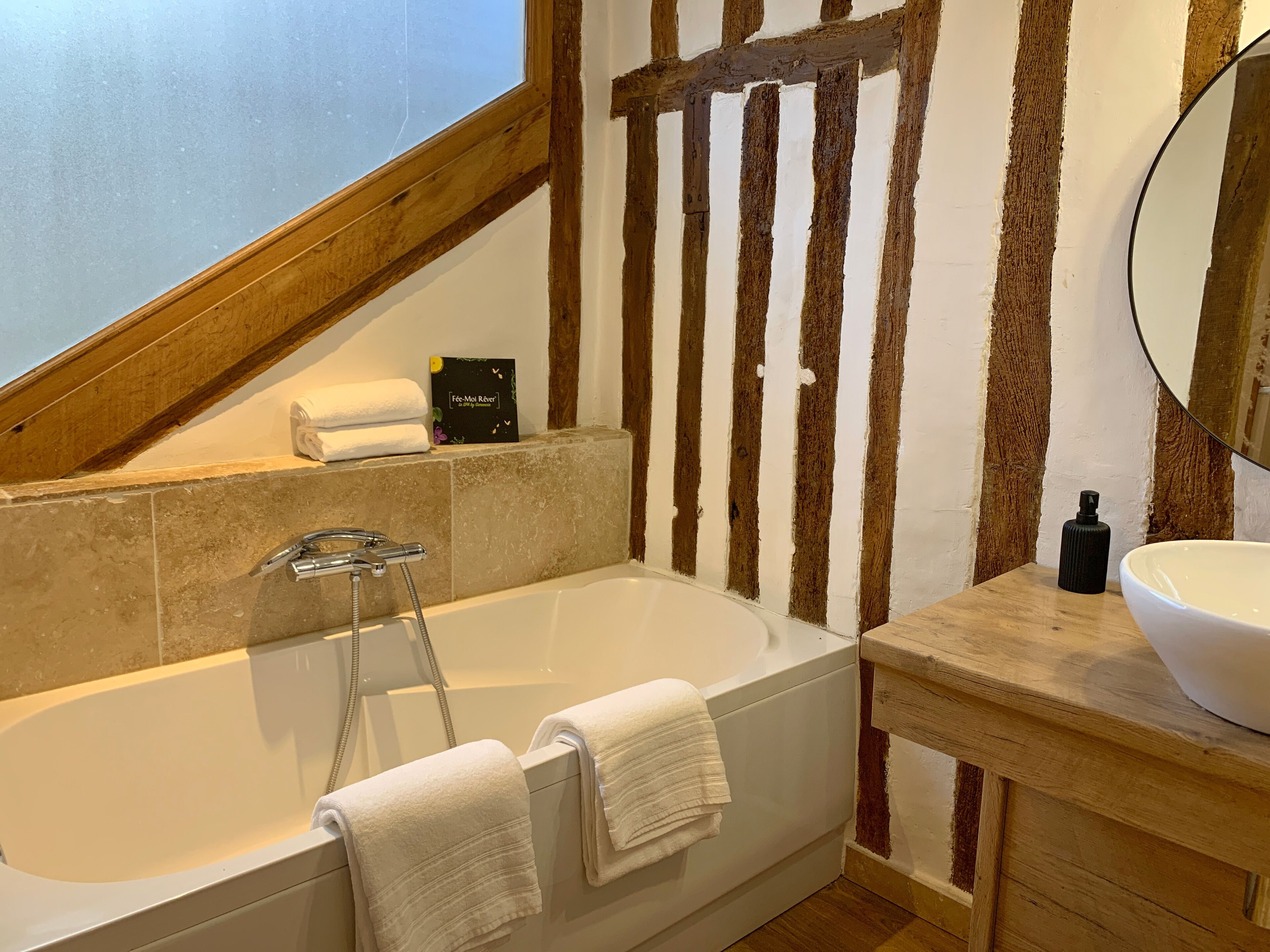 Une salle de bain moderne avec une baignoire sur pieds, un meuble-lavabo en bois et un miroir.