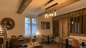 Un comedor acogedor con vigas de madera, un ventanal grande y una decoración rústica que incluye un reloj y un espejo.