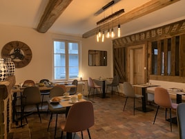 Un comedor acogedor con vigas de madera, un ventanal grande y una decoración rústica que incluye un reloj y un espejo.