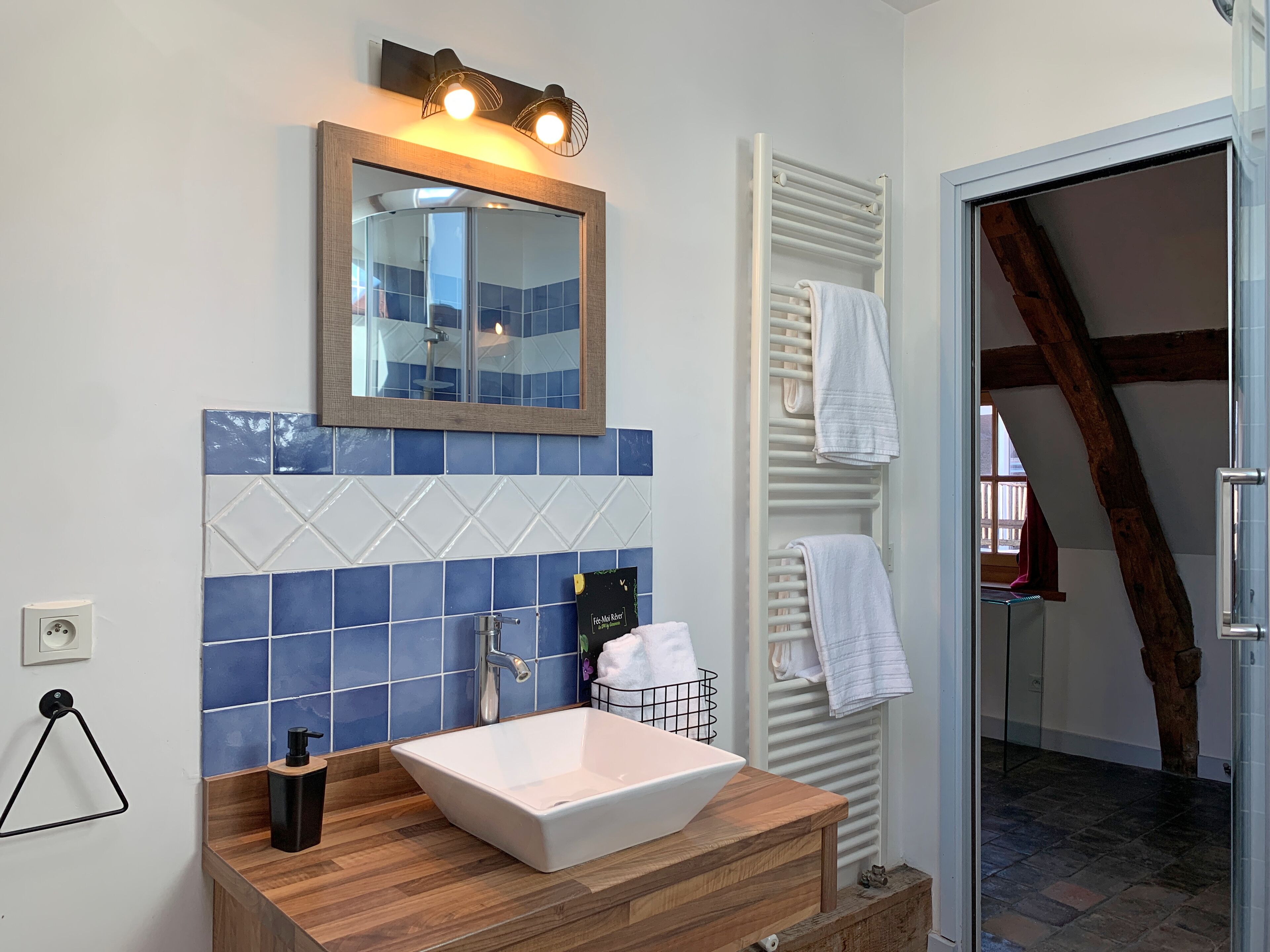 A bathroom with a white sink, blue tiles, a mirror, and a towel rack.