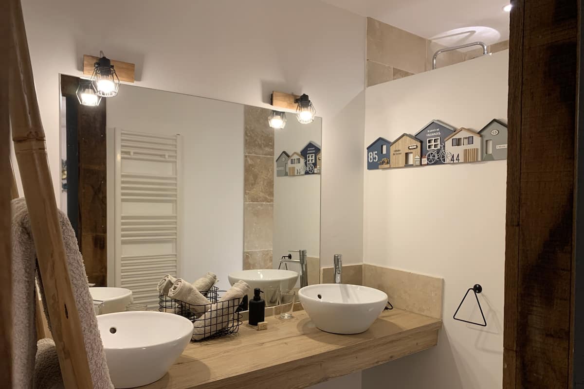 Un baño con dos lavamanos, un espejo grande y un perchero para toallas.