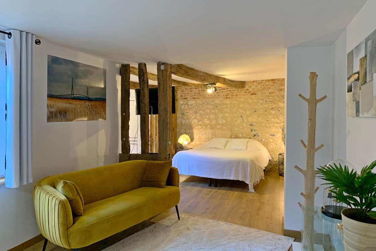 Una habitación con cama, sofá, un cuadro y pared de madera.