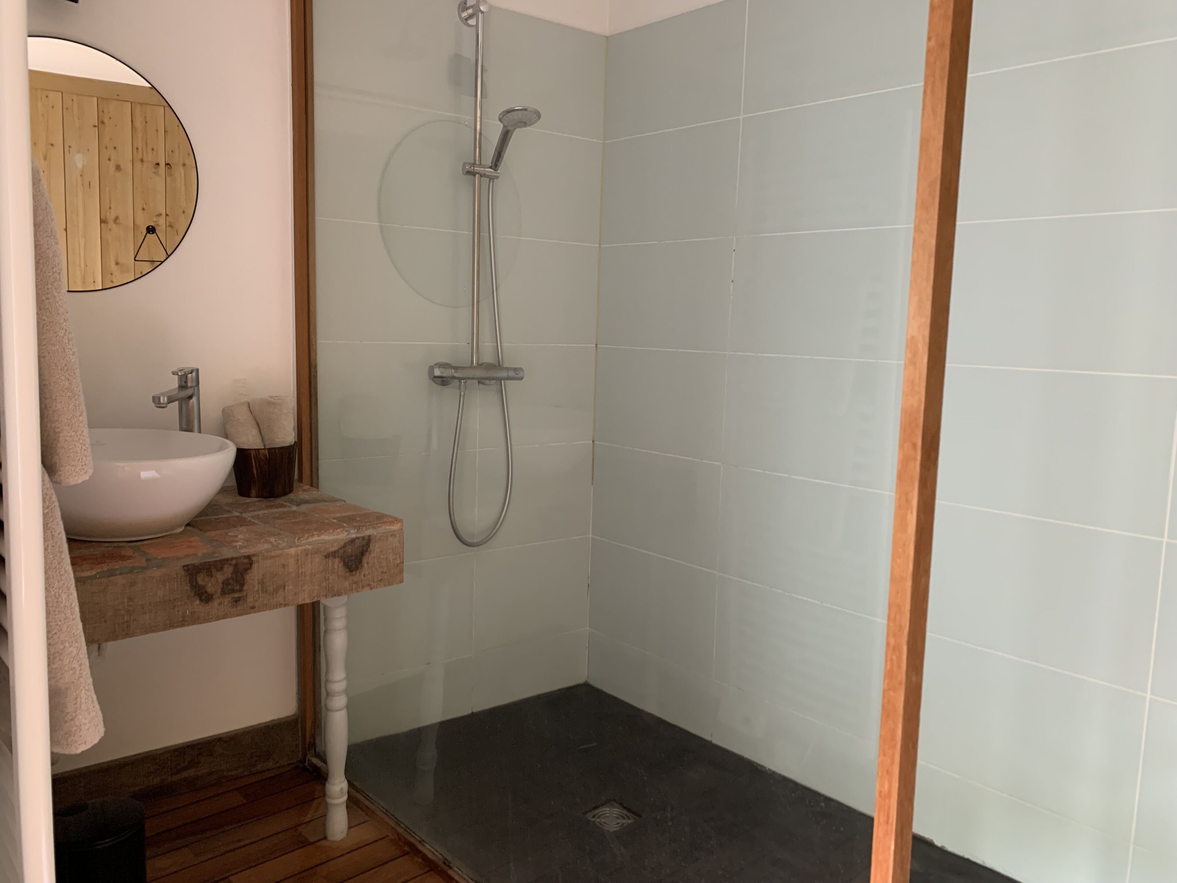 Un baño con tocador de madera, lavabo blanco y cabina de ducha.