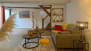 Una sala de estar acogedora con un sofá, una mesita redonda, una lámpara y una escalera.