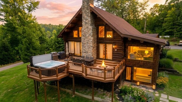 Une cabane en rondins dotée d’une terrasse, d’un bain à remous et d’un espace salon extérieur.
