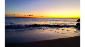 Une plage avec des vagues au coucher du soleil.