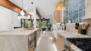 Una cocina moderna con una isla central, electrodomésticos de acero inoxidable e iluminación colgante.
