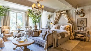 A spacious bedroom with a large bed, a chandelier, and a potted plant. - The Notary (Bruges)