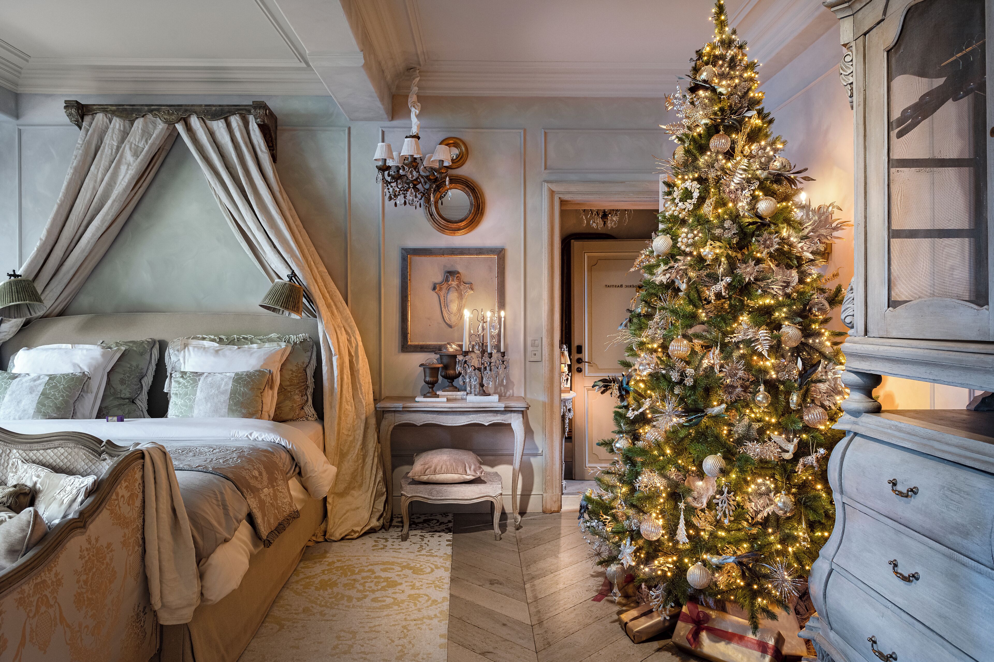 Une chambre à coucher avec un grand lit, une commode et un sapin de Noël.