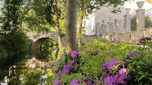 Stroll across the serene stone bridge, surrounded by lush greenery and vibrant flowers, to a peaceful haven.