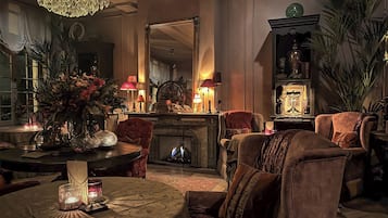 Una sala de estar acogedora con chimenea, asientos cómodos y un candelabro.