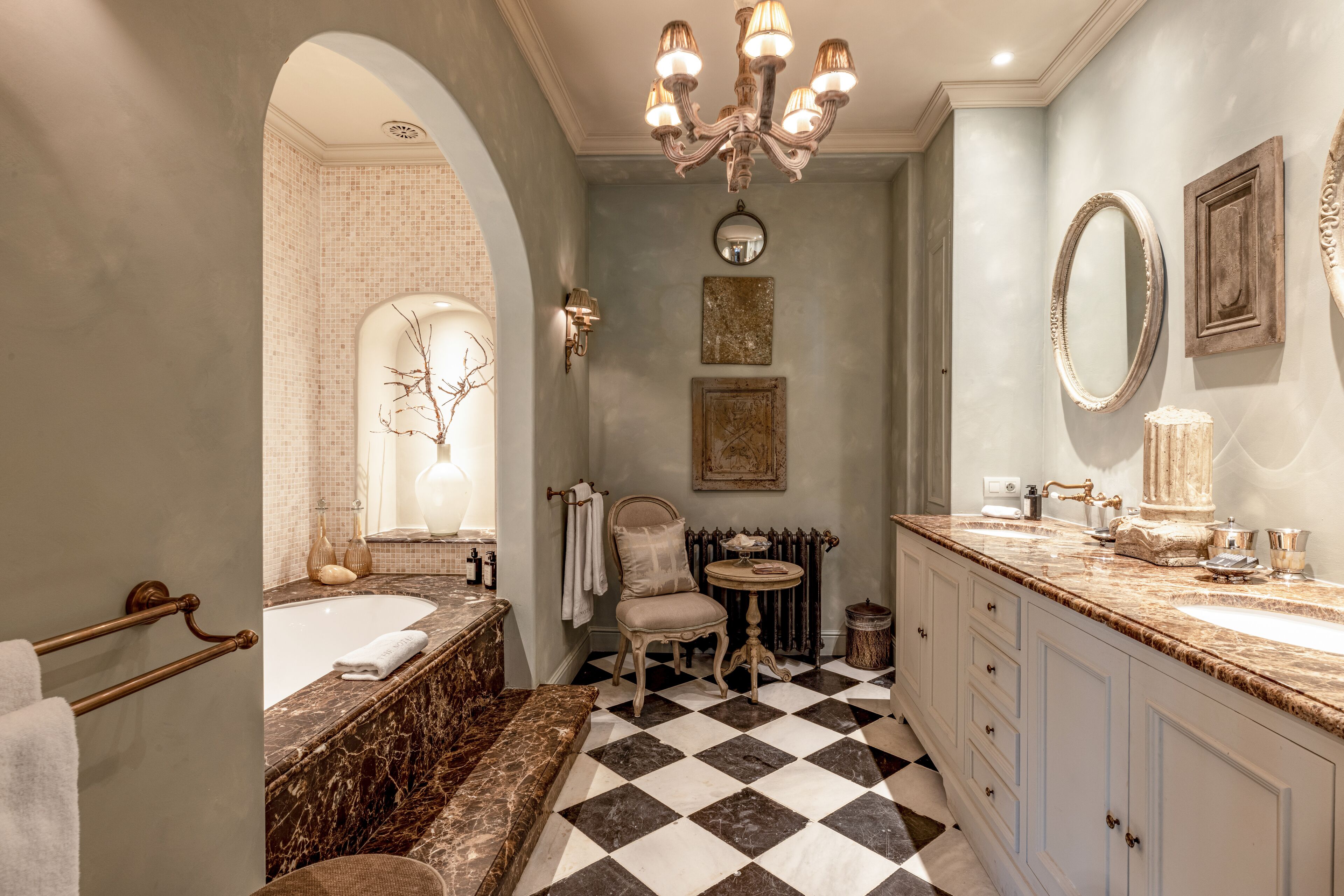 A bathroom with a checkered floor, a bathtub, a sink, and a vanity with a mirror.