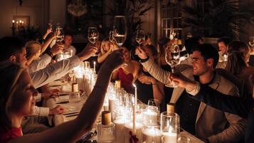 A group of people toasting at a dinner table with candles and glasses of wine.