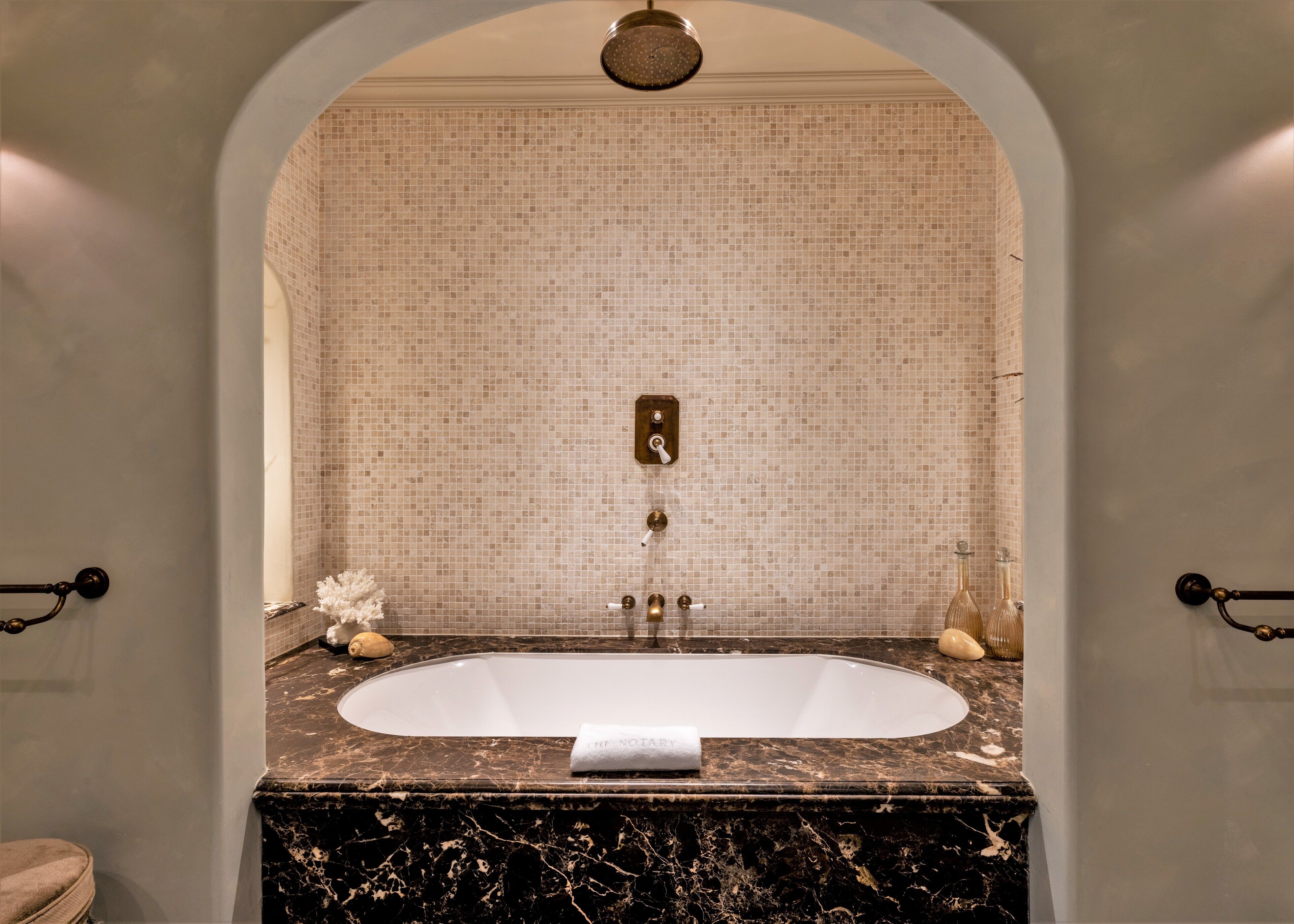 A bathroom with a freestanding bathtub, a marble countertop, and a mosaic tile wall.