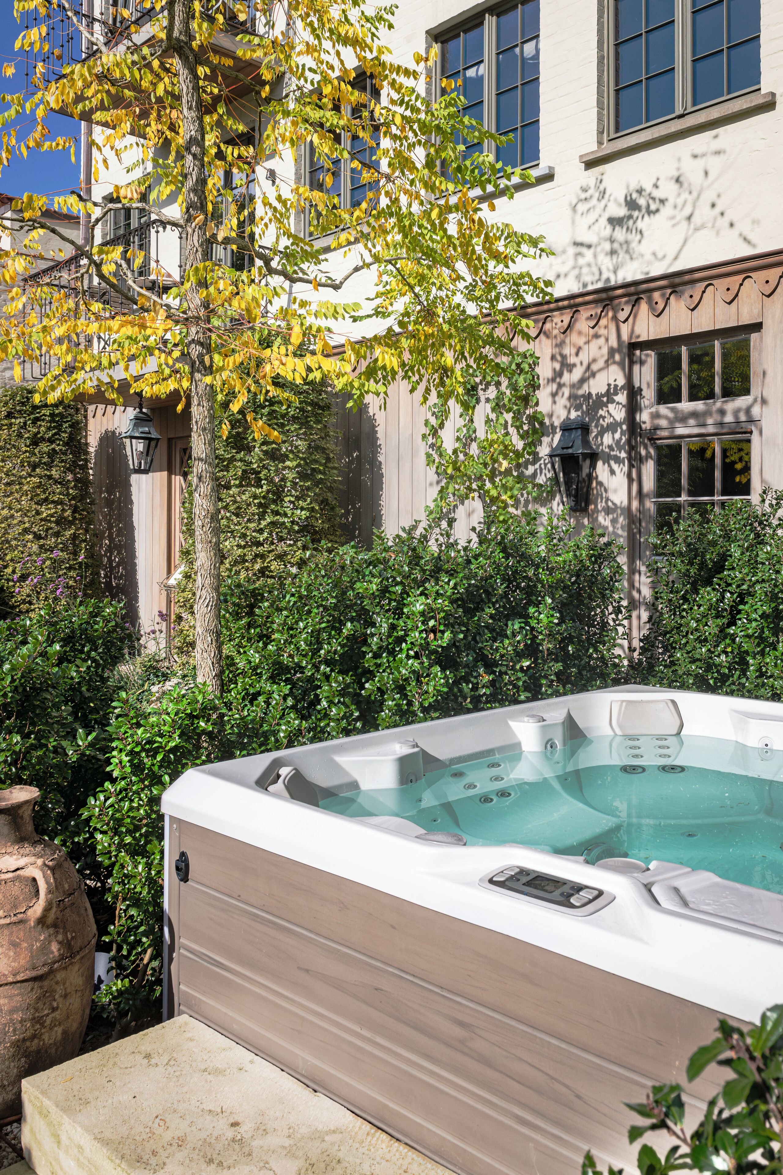 A hot tub in a garden with a building in the background.