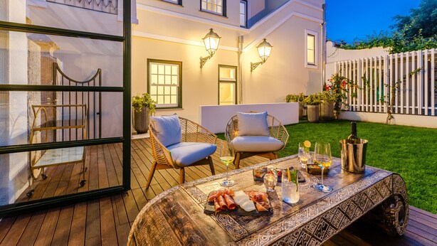 A patio with a wooden table set for dining, outdoor chairs, and a glass display case. - BCascais Boutique House by APT IIN - Cascais Center (Cascais)