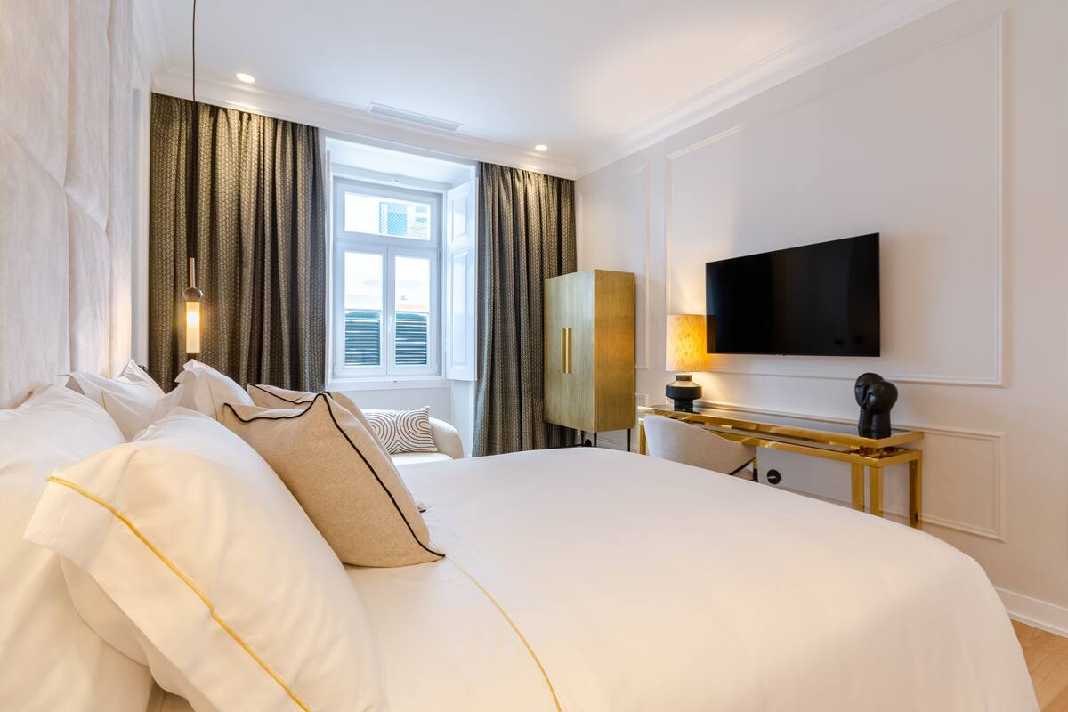 Une chambre d’hôtel avec un grand lit, un téléviseur fixé au mur, un bureau avec une lampe et une armoire.