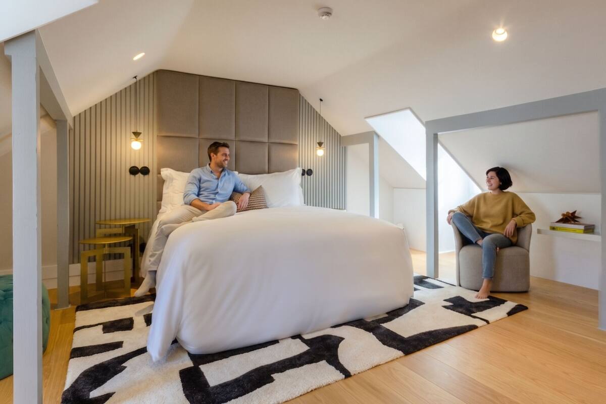 Une chambre moderne avec un grand lit, une petite table et un coin salon.
