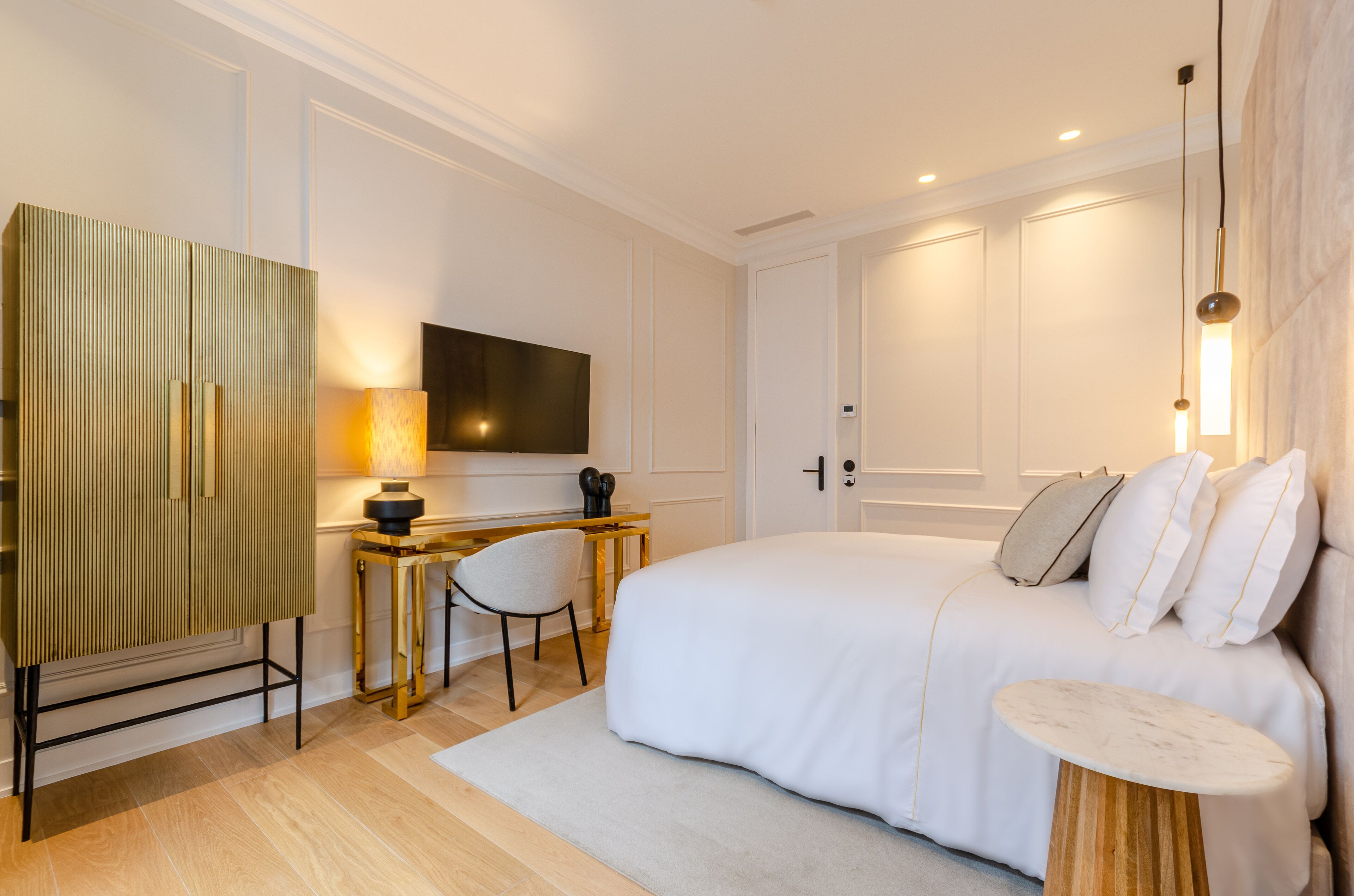 Une chambre moderne avec un grand lit, un bureau, une chaise et un téléviseur.